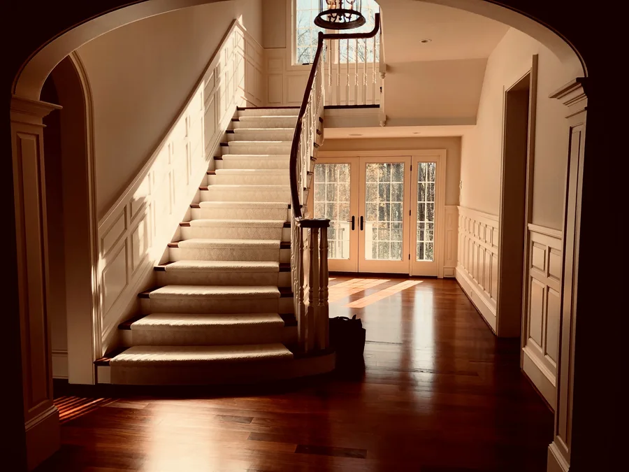Freshly painted foyer with wainscoting and natural wood staircase in a Chester Springs home by TCM Finishes