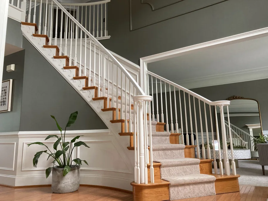 Painted staircase with sage green walls and white wainscoting in a West Chester home by TCM Finishes